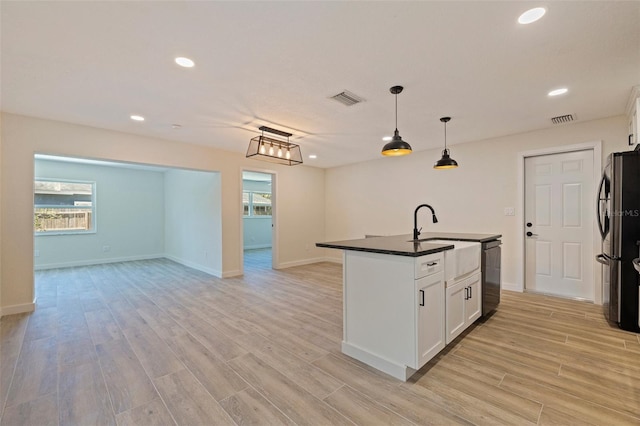 kitchen with dark countertops, dishwashing machine, visible vents, and freestanding refrigerator
