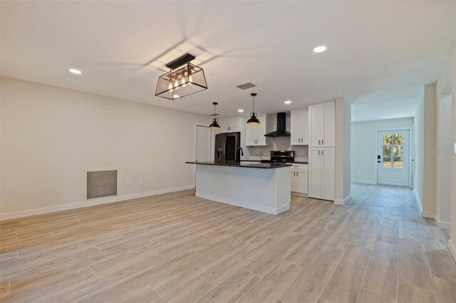 kitchen featuring dark countertops, wall chimney exhaust hood, fridge with ice dispenser, and visible vents