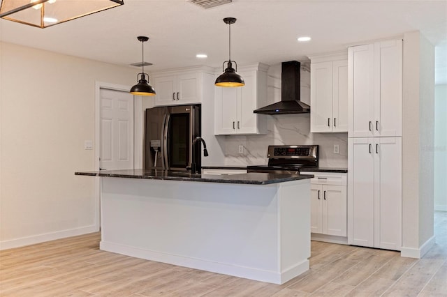 kitchen with white cabinets, wall chimney range hood, baseboards, a kitchen island with sink, and appliances with stainless steel finishes