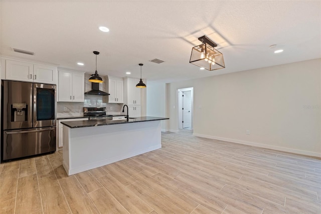 kitchen featuring white cabinets, a sink, visible vents, wall chimney range hood, and appliances with stainless steel finishes