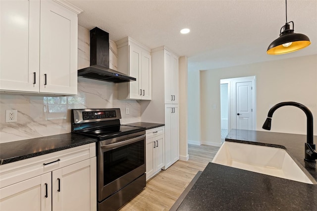 kitchen featuring tasteful backsplash, a sink, stainless steel electric range oven, light wood-type flooring, and wall chimney exhaust hood