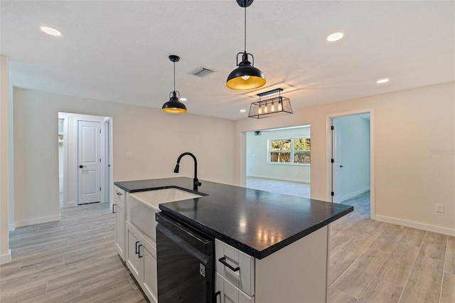 kitchen with dark countertops, dishwasher, light wood-style floors, and a sink