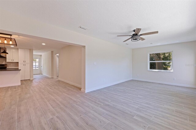 spare room featuring light wood-type flooring, baseboards, visible vents, and ceiling fan