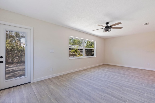 empty room with light wood-type flooring, plenty of natural light, a ceiling fan, and visible vents