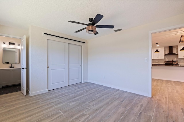 unfurnished bedroom featuring a closet, light wood-type flooring, visible vents, and a sink