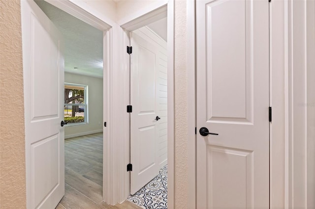 corridor featuring baseboards and light wood finished floors