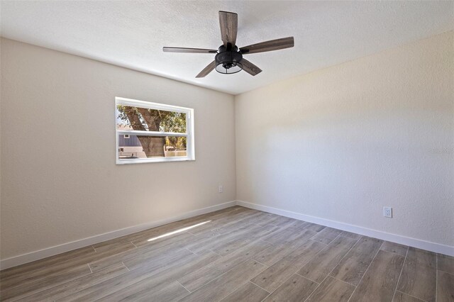 empty room with baseboards, a ceiling fan, and wood finished floors