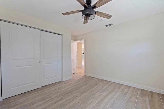 unfurnished bedroom featuring light wood-type flooring, baseboards, visible vents, and a closet