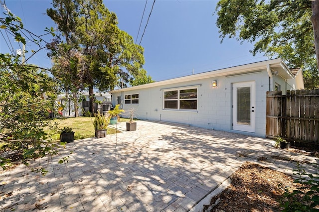 back of house featuring concrete block siding, a patio area, and fence