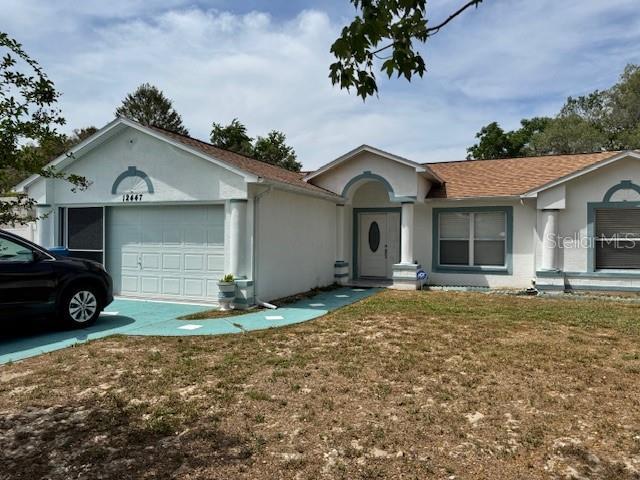 single story home with a garage, stucco siding, and a front lawn
