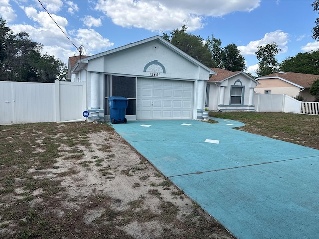 ranch-style home with a garage, fence, stucco siding, and driveway
