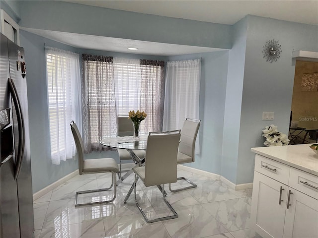 dining space with baseboards and marble finish floor