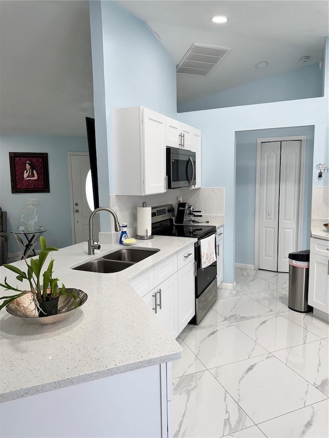 kitchen featuring visible vents, a peninsula, light stone counters, a sink, and appliances with stainless steel finishes