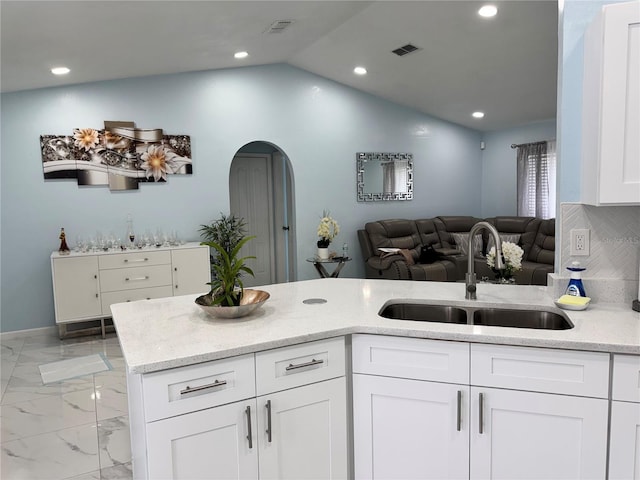 kitchen featuring light stone countertops, a sink, arched walkways, marble finish floor, and open floor plan