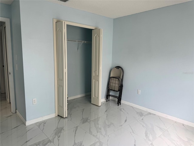 unfurnished bedroom with baseboards, a closet, and marble finish floor