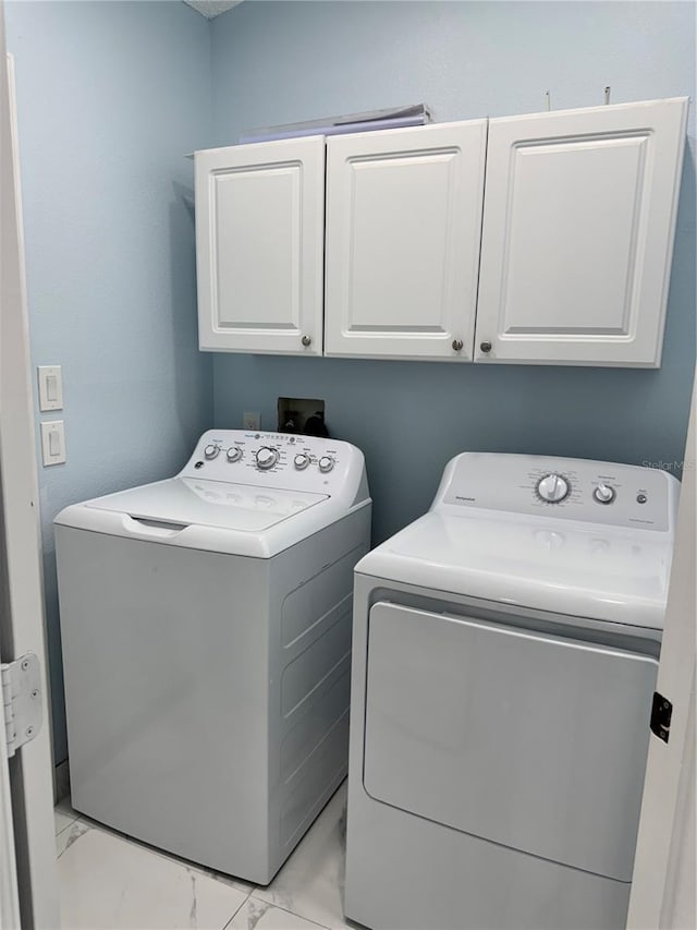 washroom featuring separate washer and dryer, marble finish floor, and cabinet space