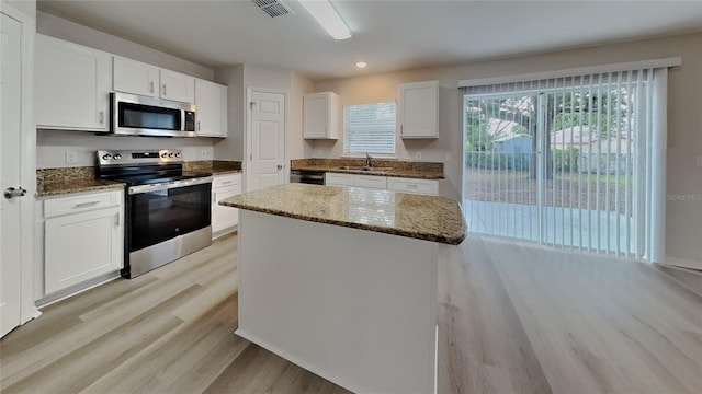105 Evergreen Dr, Auburndale, FL 33823 - kitchen featuring appliances with stainless steel finishes, a sink, light wood-style flooring, white cabinets, and dark stone counters