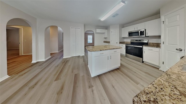 105 Evergreen Dr, Auburndale, FL 33823 - kitchen with visible vents, light wood-style flooring, white cabinetry, light stone countertops, and appliances with stainless steel finishes
