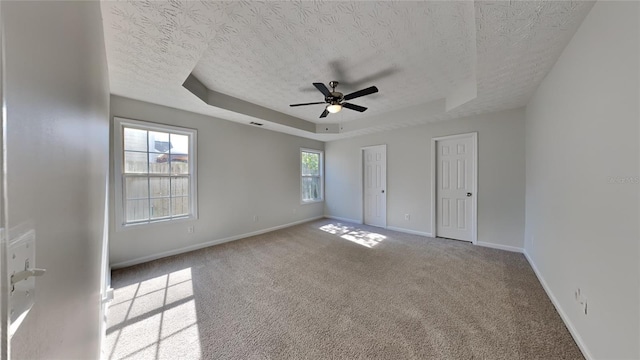 105 Evergreen Dr, Auburndale, FL 33823 - unfurnished bedroom featuring a textured ceiling, multiple closets, carpet floors, a tray ceiling, and baseboards