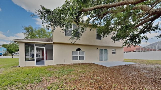 105 Evergreen Dr, Auburndale, FL 33823 - rear view of property featuring a sunroom, stucco siding, fence, a lawn, and a patio area