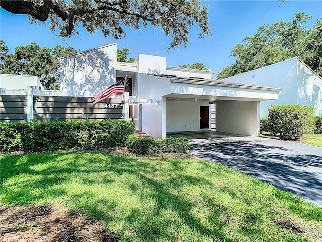 4137 Northmeadow Cir, Tampa, FL 33618 - view of front of house with a carport, driveway, fence, a front yard, and stucco siding