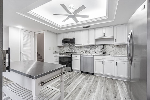 4137 Northmeadow Cir, Tampa, FL 33618 - kitchen featuring white cabinets, stainless steel appliances, a tray ceiling, a sink, and ceiling fan