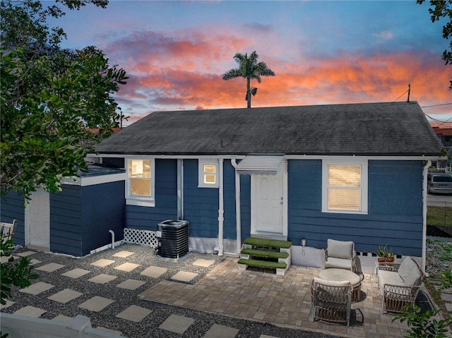exterior space with a patio, roof with shingles, and central air condition unit