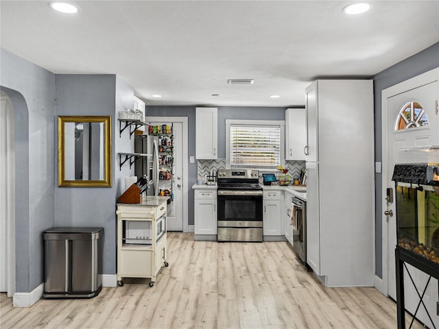 kitchen with light countertops, tasteful backsplash, appliances with stainless steel finishes, and light wood-type flooring