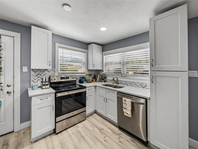 kitchen featuring tasteful backsplash, appliances with stainless steel finishes, light countertops, and a sink
