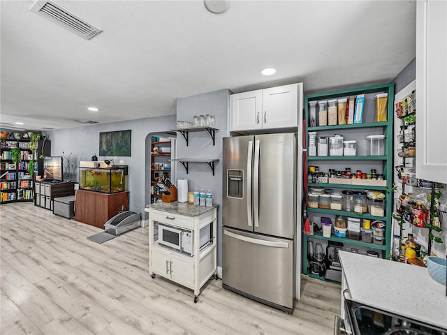 kitchen with appliances with stainless steel finishes, visible vents, open shelves, and light wood finished floors