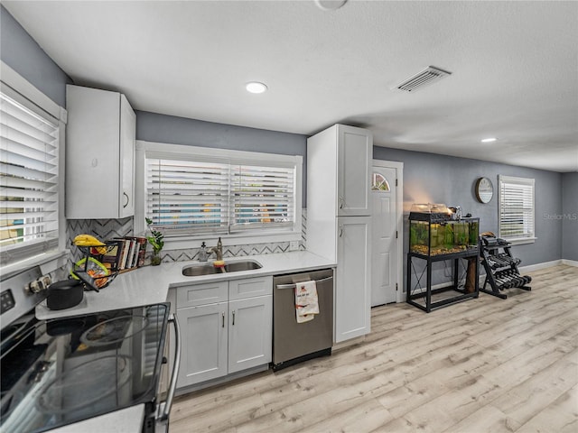kitchen featuring a sink, stainless steel appliances, visible vents, backsplash, and light countertops