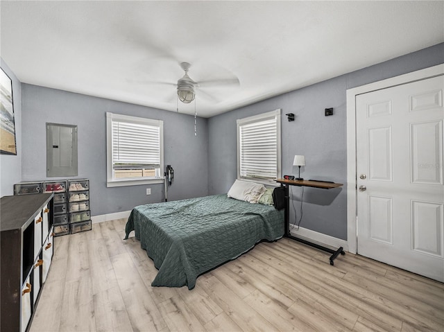bedroom featuring baseboards, wood finished floors, a ceiling fan, and electric panel