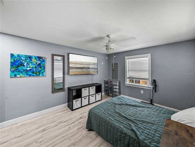 bedroom with a ceiling fan, electric panel, wood finished floors, and baseboards