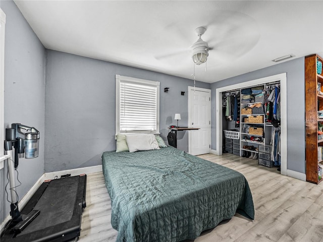 bedroom featuring wood finished floors, a closet, baseboards, visible vents, and a ceiling fan