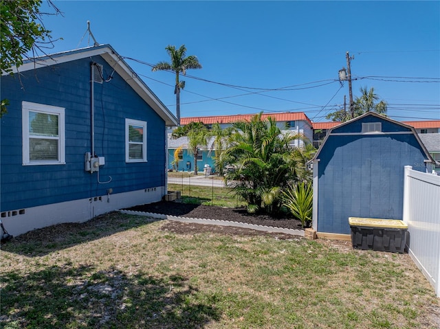 view of yard with fence, a shed, and an outbuilding