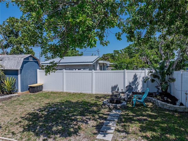 view of yard featuring a fire pit, a fenced backyard, a shed, and an outdoor structure