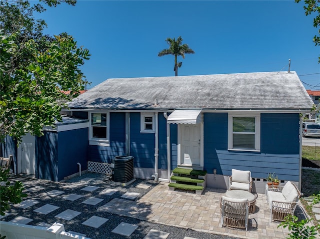 view of front of home featuring a shingled roof, a patio, and central AC unit