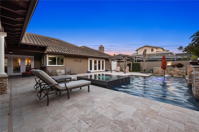 6129 Leeland St S, Saint Petersburg, FL 33715 - pool at dusk featuring an in ground hot tub, fence, a patio area, and french doors