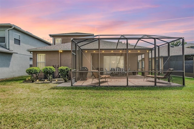 7815 Blue Spring Dr, Land O Lakes, FL 34637 - back of house at dusk with glass enclosure, a yard, a patio, and stucco siding