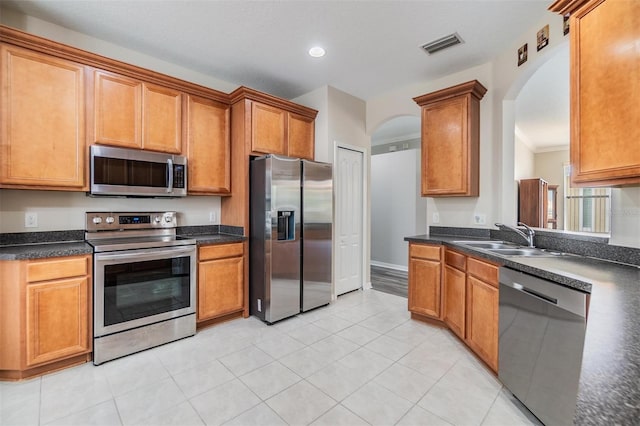 7815 Blue Spring Dr, Land O Lakes, FL 34637 - kitchen featuring stainless steel appliances, dark countertops, visible vents, a sink, and arched walkways