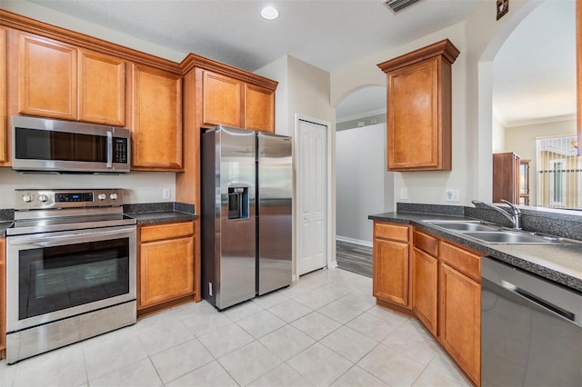 7815 Blue Spring Dr, Land O Lakes, FL 34637 - kitchen with arched walkways, brown cabinets, stainless steel appliances, and a sink