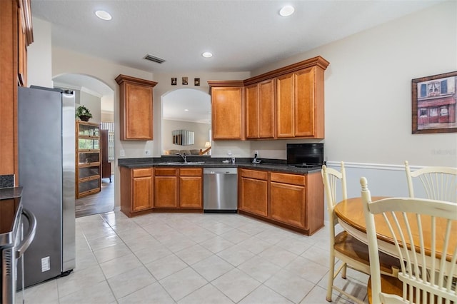 7815 Blue Spring Dr, Land O Lakes, FL 34637 - kitchen featuring arched walkways, visible vents, appliances with stainless steel finishes, and brown cabinets