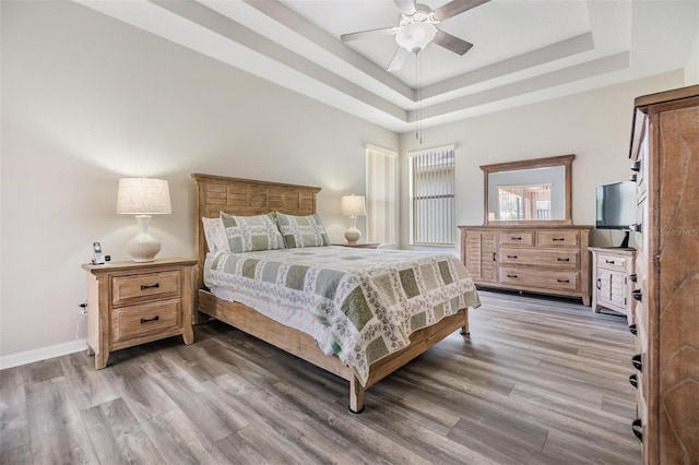 7815 Blue Spring Dr, Land O Lakes, FL 34637 - bedroom with light wood-type flooring, ceiling fan, baseboards, and a raised ceiling