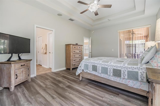 7815 Blue Spring Dr, Land O Lakes, FL 34637 - bedroom with a tray ceiling, ensuite bathroom, baseboards, wood finished floors, and access to outside