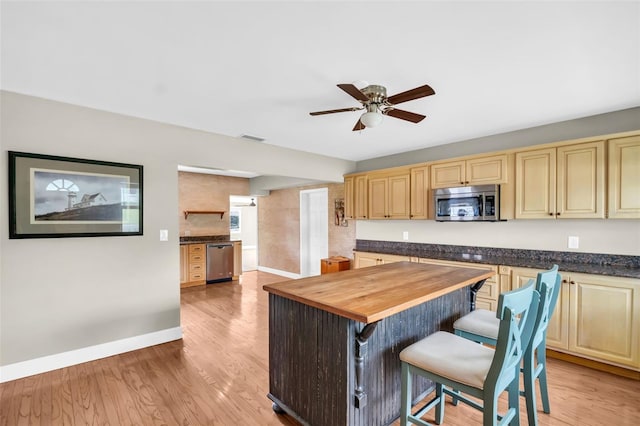 250 W Canal Dr, Palm Harbor, FL 34684 - kitchen with appliances with stainless steel finishes, wood counters, a center island, a ceiling fan, and a kitchen bar