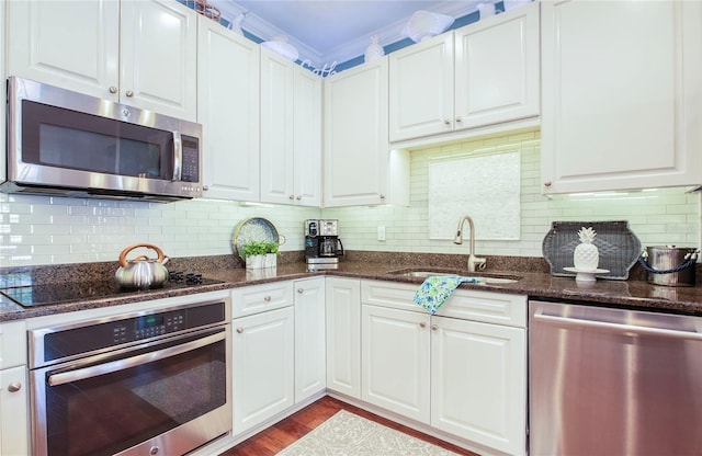 6303 Vista Verde Dr E, Gulfport, FL 33707 - kitchen featuring appliances with stainless steel finishes, tasteful backsplash, wood finished floors, a sink, and white cabinets
