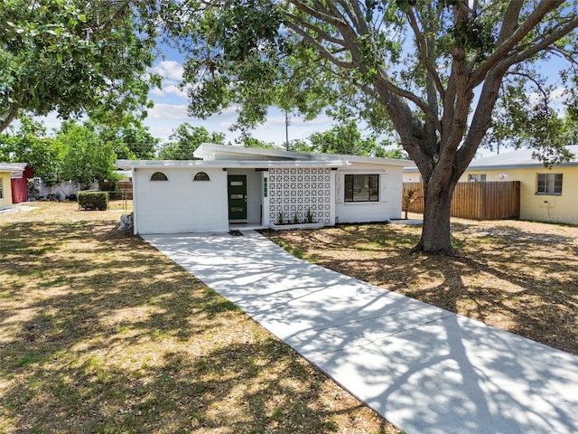 mid-century modern home featuring fence and driveway
