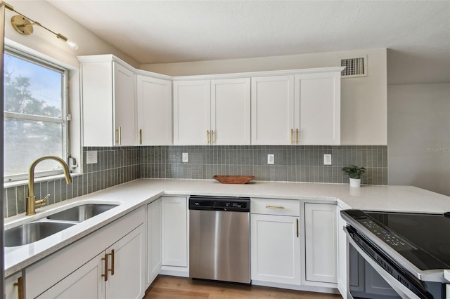 kitchen featuring stainless steel appliances, a sink, white cabinetry, and decorative backsplash