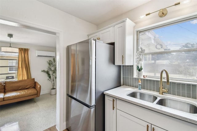 kitchen with a sink, freestanding refrigerator, a wall mounted air conditioner, and plenty of natural light