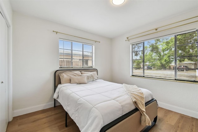 bedroom featuring multiple windows, baseboards, and wood finished floors